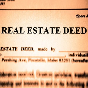 Close-up of a real estate deed document with the title 'REAL ESTATE DEED' highlighted in focus.