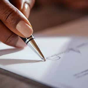 Close-up of a hand signing a loan agreement document in a financing transaction