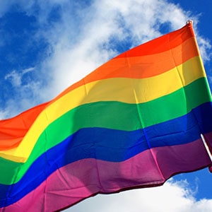 Vibrant pride flag against clouds, showcasing LGBTQ+ community support.